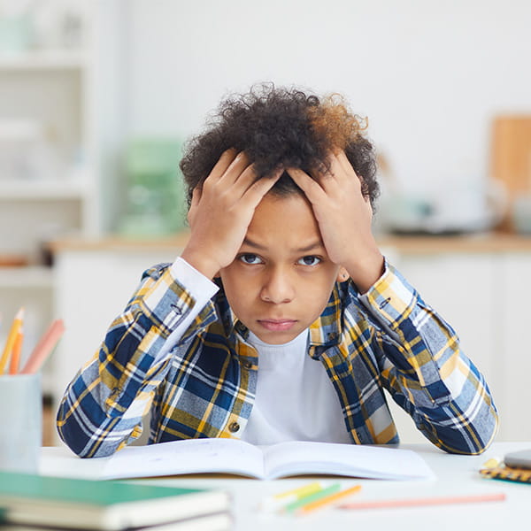 A student appearing overwhelmed with his hands on his head