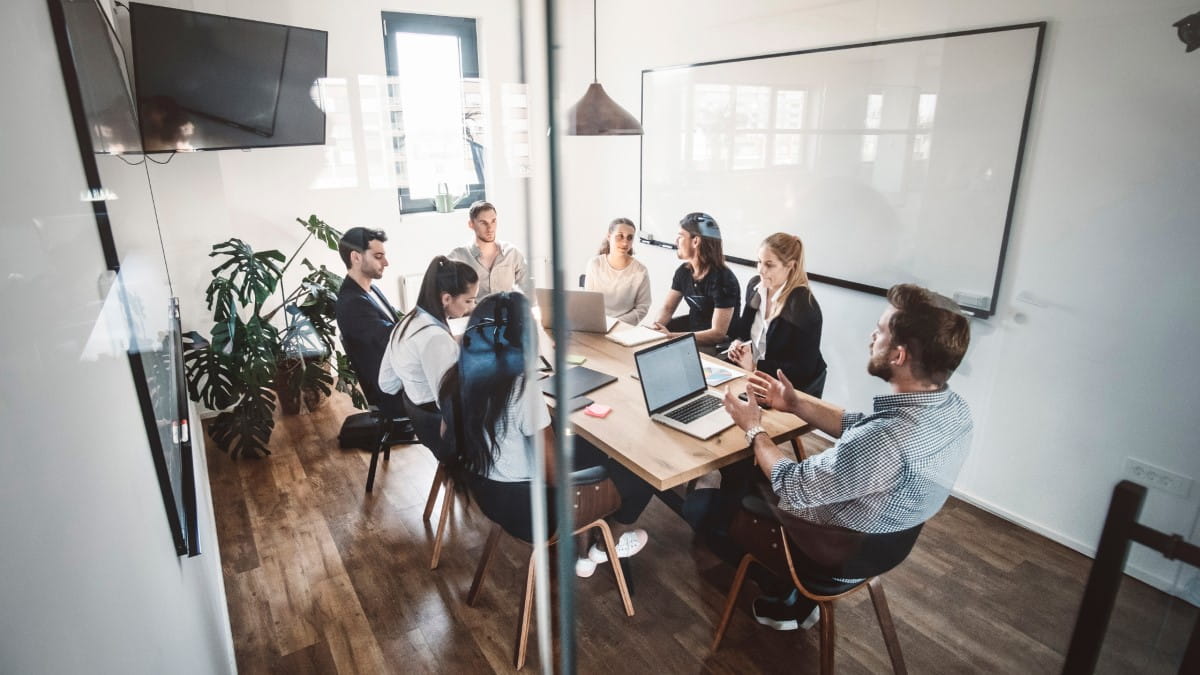 A group of professionals sitting together in a plain, technology-free meeting room.