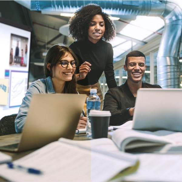 Four professionals gathered in a boardroom, laughing and collaborating in a meeting.