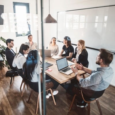 A group of professionals sitting together in a plain, technology-free meeting room.