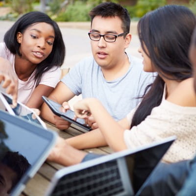 High school aged students collaborating over their individual tablets.