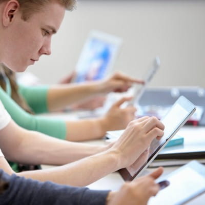 A middle-school aged student working independently on a tablet.