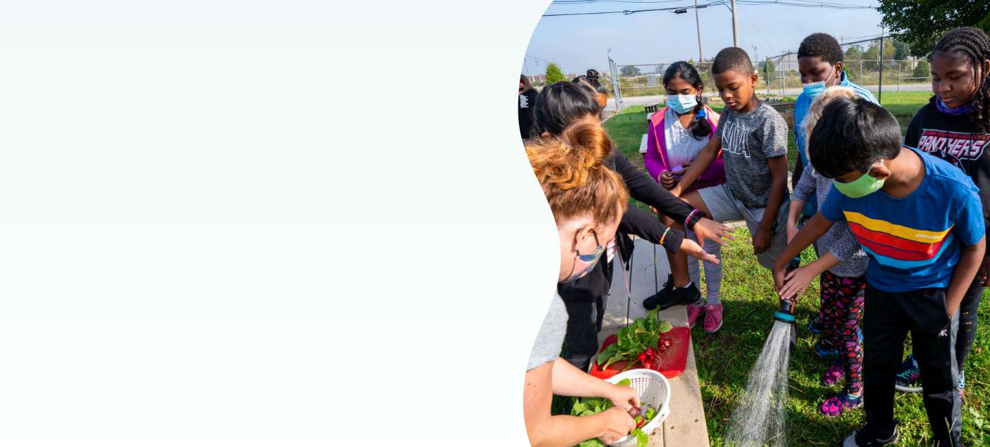 Diverse group of students learning about sustainability through a gardening project outdoors.