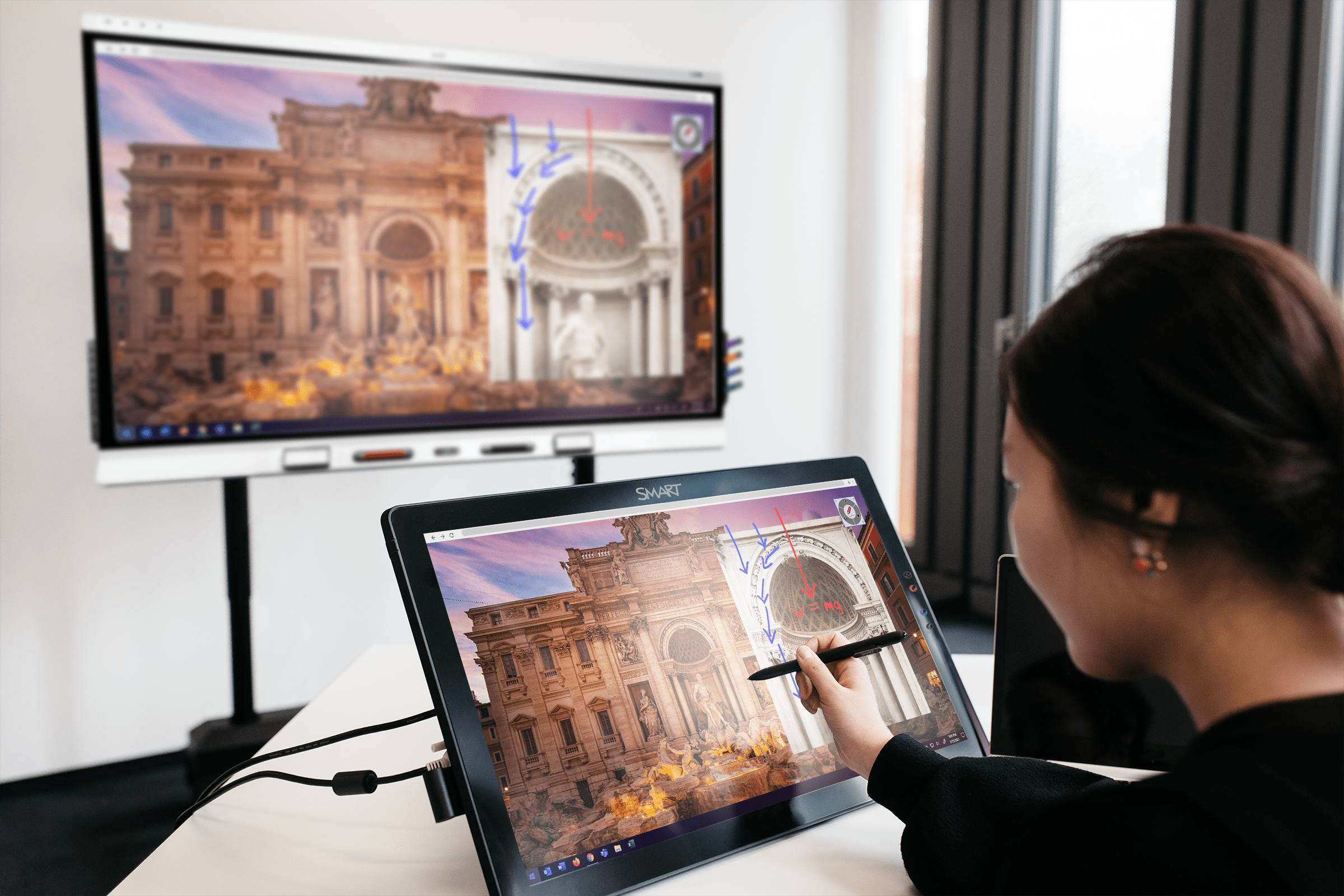 A teacher annotates on an image on her device. The annotation is then reflected on her interactive display.