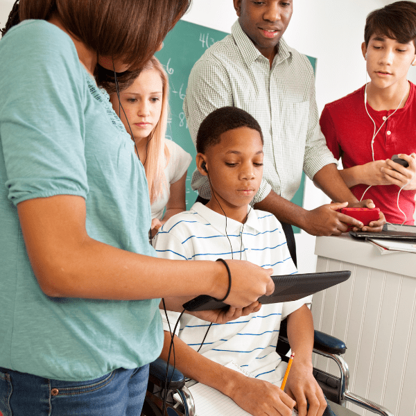 Teachers and classmates gathered around a tablet listening to audio accommodations.