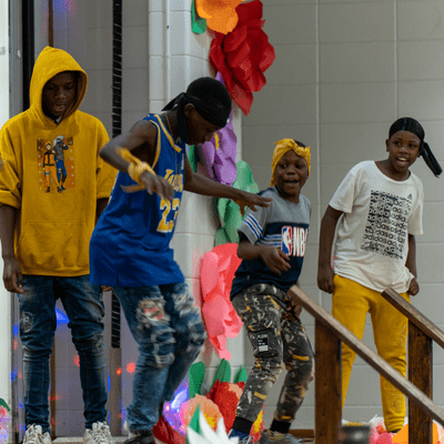 Four students dancing at school assembly